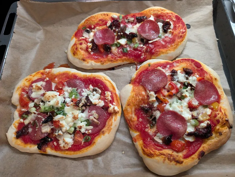 Drei selbstgemachte Pizzen auf dem Blech